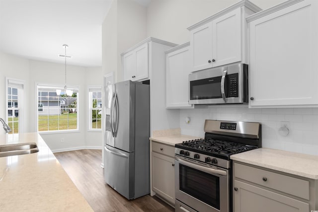 kitchen featuring stainless steel appliances, a sink, dark wood-style flooring, backsplash, and a chandelier