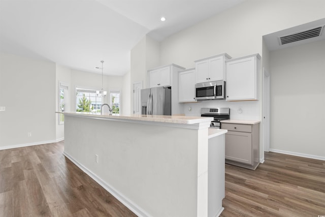 kitchen with stainless steel appliances, a kitchen island with sink, dark wood finished floors, light countertops, and recessed lighting
