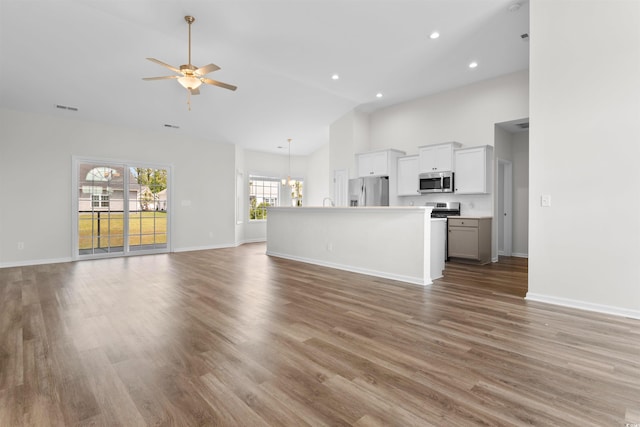 unfurnished living room with a ceiling fan, high vaulted ceiling, baseboards, light wood-type flooring, and recessed lighting