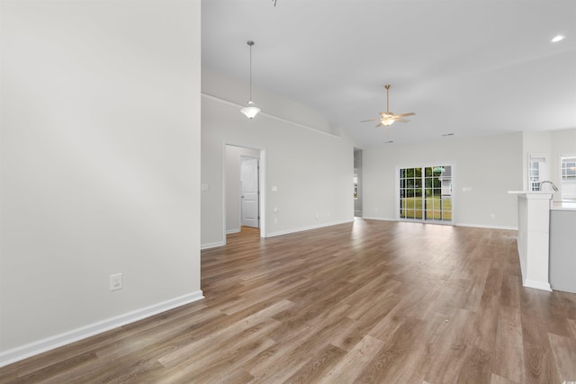 unfurnished living room with a ceiling fan, light wood-style flooring, baseboards, and lofted ceiling
