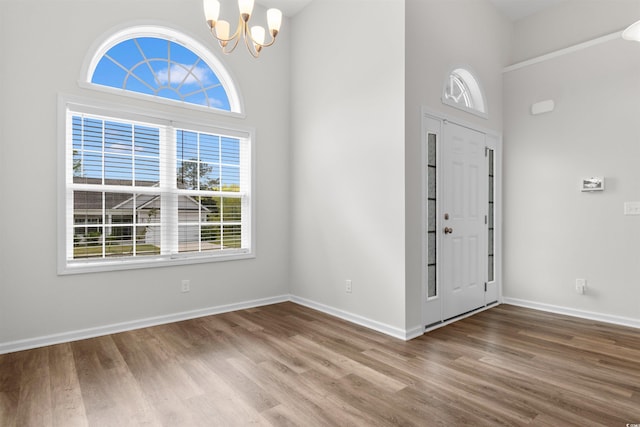 entrance foyer with a chandelier, wood finished floors, a towering ceiling, and baseboards