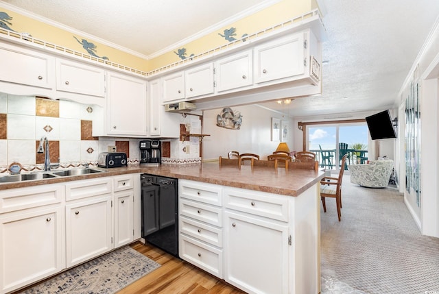 kitchen with a sink, dishwasher, a peninsula, crown molding, and white cabinets