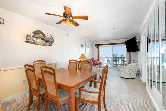 dining room with light colored carpet, ceiling fan, ornamental molding, and baseboards