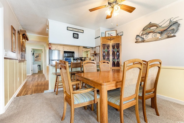 dining room with light colored carpet, crown molding, ceiling fan, baseboards, and a textured ceiling