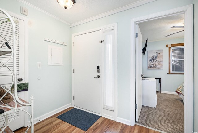 foyer entrance featuring wood finished floors, ornamental molding, baseboards, and a textured ceiling