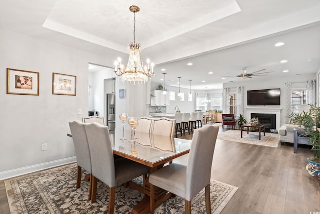 dining area with recessed lighting, light wood finished floors, a glass covered fireplace, baseboards, and ceiling fan with notable chandelier