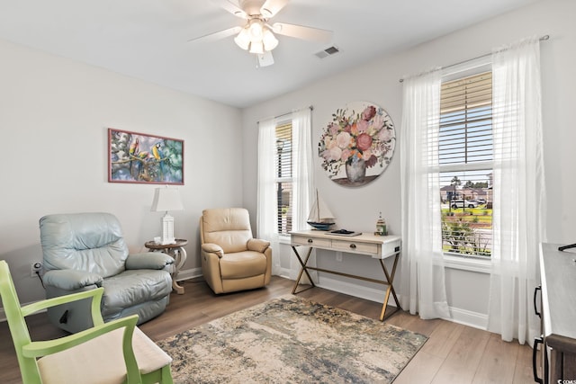 living area featuring visible vents, ceiling fan, wood finished floors, and baseboards
