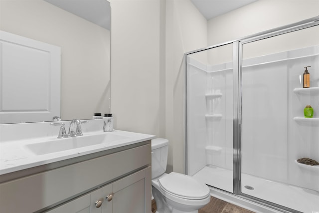 bathroom featuring a shower stall, toilet, vanity, and wood finished floors