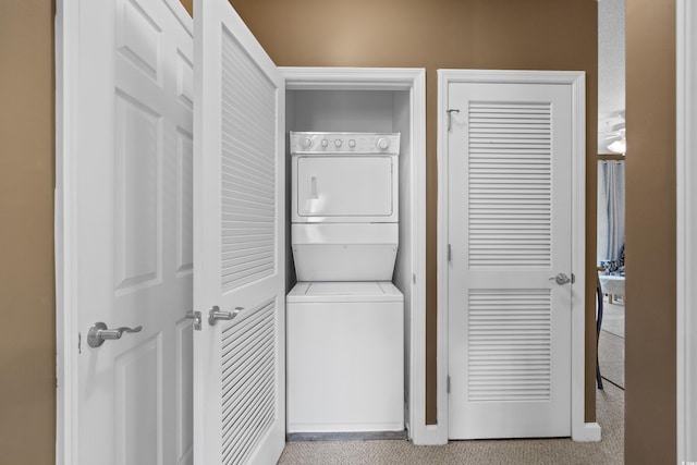 laundry area featuring stacked washing maching and dryer, baseboards, and laundry area