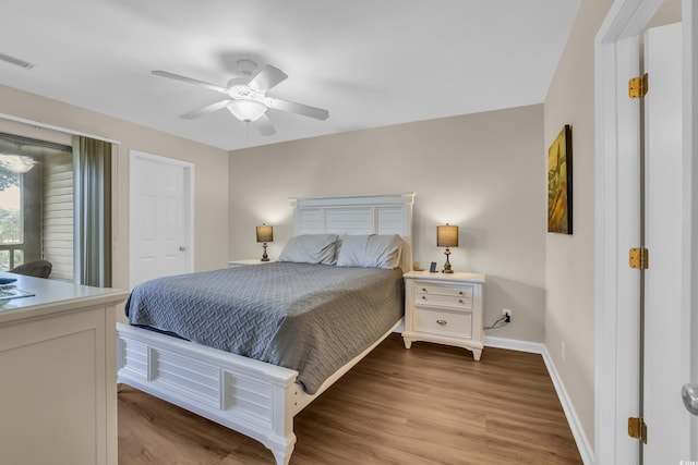 bedroom with baseboards, a ceiling fan, wood finished floors, and visible vents