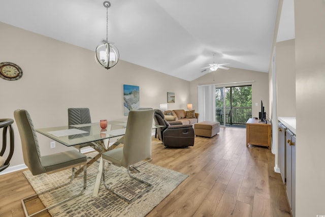 dining room featuring light wood-style floors, vaulted ceiling, and ceiling fan with notable chandelier