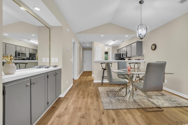 dining area featuring light wood-type flooring, baseboards, and vaulted ceiling