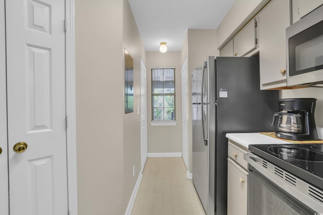 kitchen featuring light countertops, baseboards, stainless steel microwave, and electric range