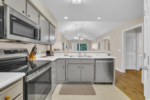 kitchen featuring a sink, light countertops, stainless steel appliances, a peninsula, and lofted ceiling