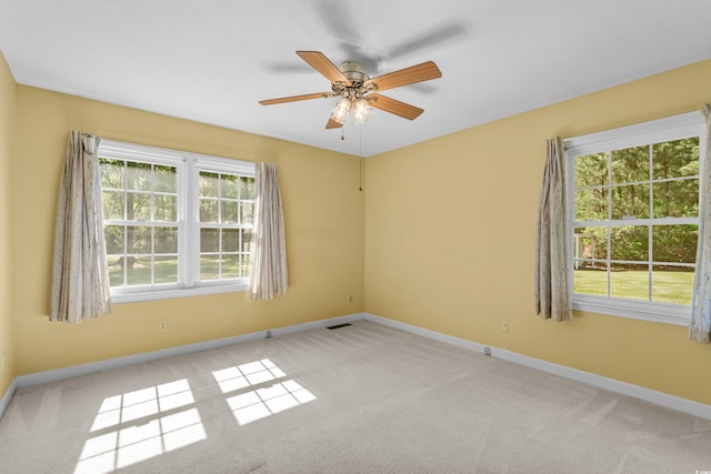 spare room featuring light carpet, visible vents, baseboards, and a ceiling fan