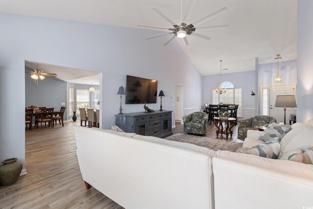1752 Starbridge Dr, Surfside Beach, SC 29575 - living room featuring baseboards, high vaulted ceiling, light wood-style floors, and ceiling fan with notable chandelier