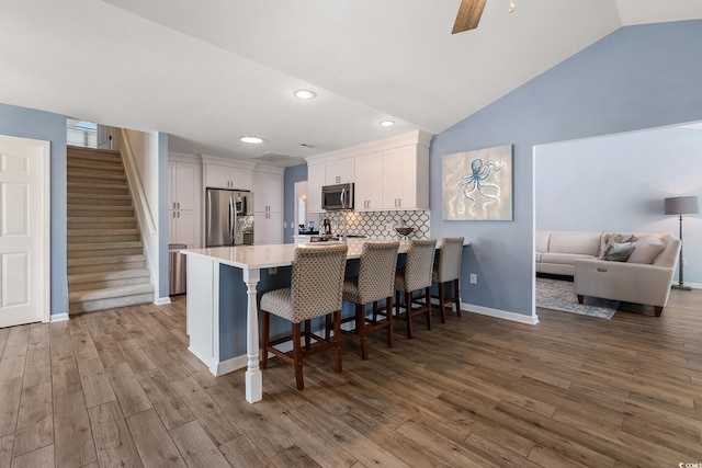 1752 Starbridge Dr, Surfside Beach, SC 29575 - kitchen with a peninsula, white cabinets, wood finished floors, stainless steel appliances, and a breakfast bar area
