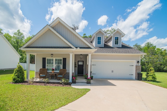 craftsman-style house with board and batten siding, covered porch, a front yard, concrete driveway, and an attached garage