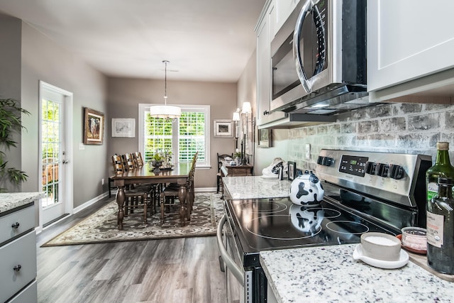 kitchen featuring white cabinetry, stainless steel appliances, baseboards, dark wood-type flooring, and backsplash