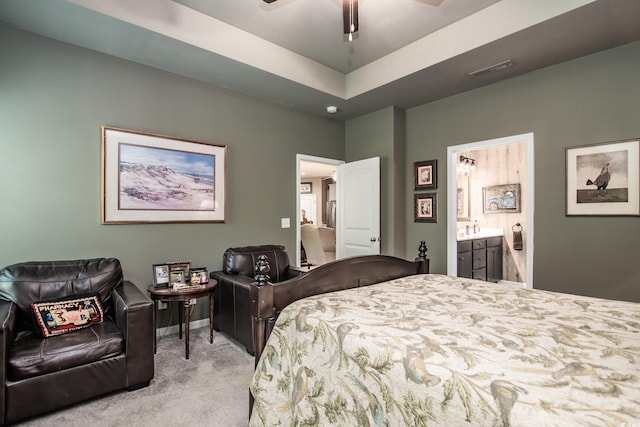 bedroom with connected bathroom, a tray ceiling, visible vents, carpet, and baseboards
