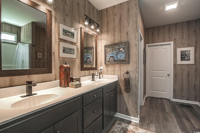 bathroom featuring wood finished floors, wooden walls, and a sink