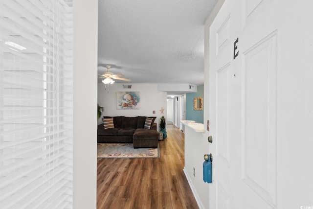 hallway with wood finished floors, visible vents, and a textured ceiling