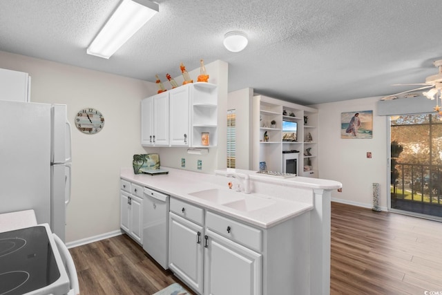 kitchen with open shelves, a sink, a textured ceiling, white appliances, and dark wood-type flooring
