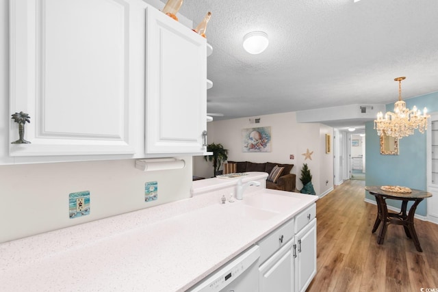 kitchen with white cabinets, a chandelier, a textured ceiling, and light countertops