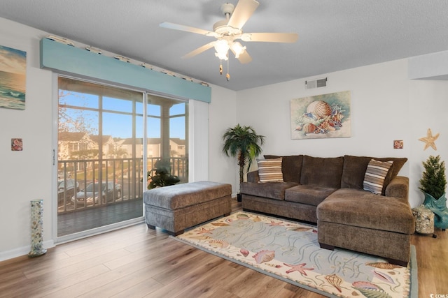 living room featuring baseboards, a ceiling fan, wood finished floors, and visible vents