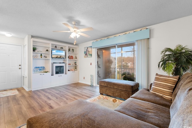 living area featuring ceiling fan, baseboards, wood finished floors, and a textured ceiling