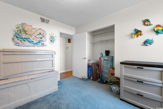 bedroom with a closet, a textured ceiling, visible vents, and carpet