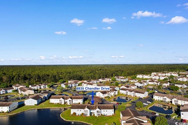 drone / aerial view with a residential view, a wooded view, and a water view