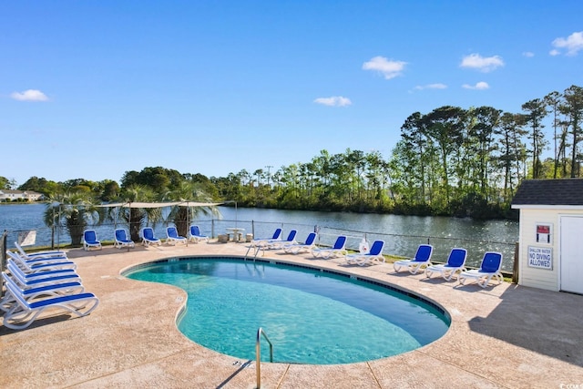 pool featuring fence, a water view, and a patio area