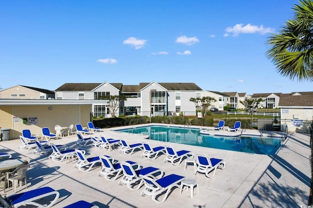 community pool featuring a patio area, fence, and a residential view