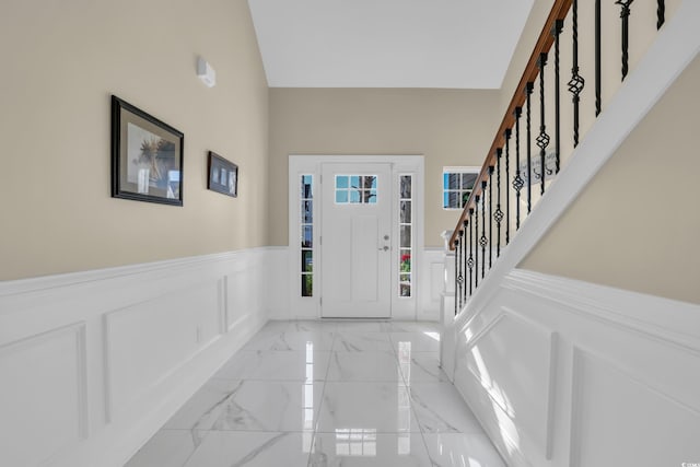 entryway featuring a wainscoted wall, a decorative wall, stairs, and marble finish floor