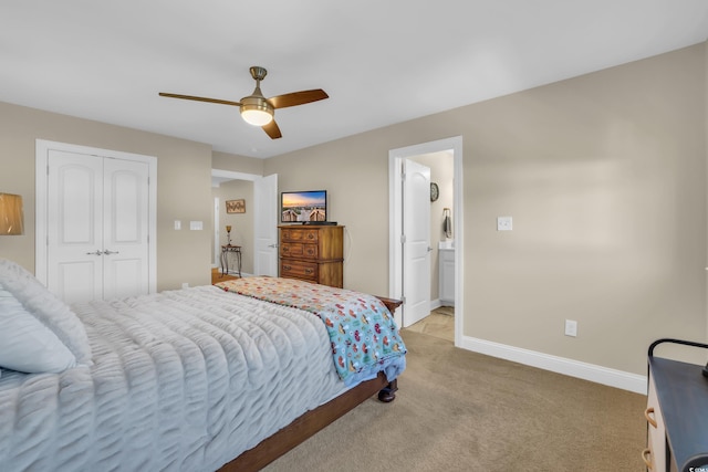 bedroom featuring ceiling fan, light carpet, baseboards, ensuite bathroom, and a closet