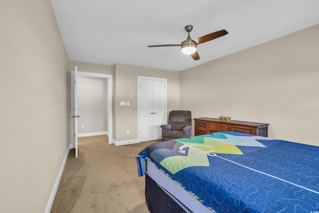 bedroom featuring light colored carpet, baseboards, ceiling fan, and a closet