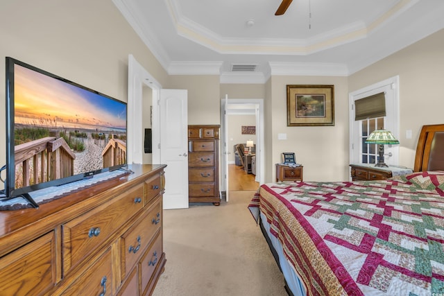 bedroom with visible vents, light carpet, ornamental molding, and a raised ceiling