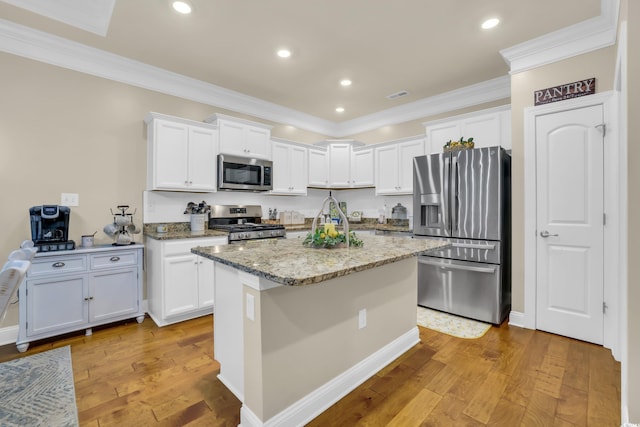 kitchen featuring crown molding, appliances with stainless steel finishes, white cabinets, and light stone countertops