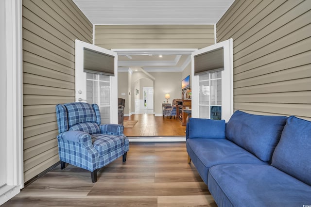 interior space featuring arched walkways, wood walls, french doors, wood finished floors, and ornamental molding