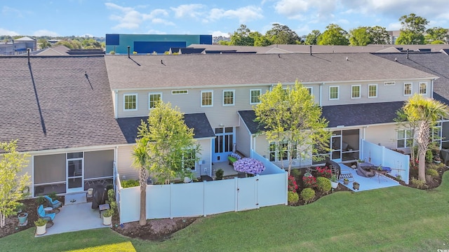 rear view of house with a fenced backyard, a patio, a shingled roof, and a yard