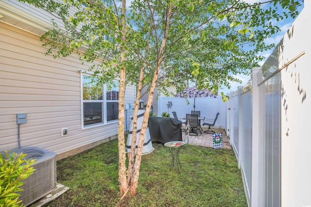 view of yard with outdoor dining space, central AC unit, a fenced backyard, and a patio area