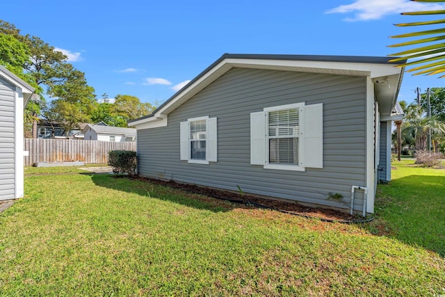 view of side of property featuring a lawn and fence