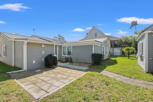 back of property featuring fence, a patio, a lawn, and metal roof