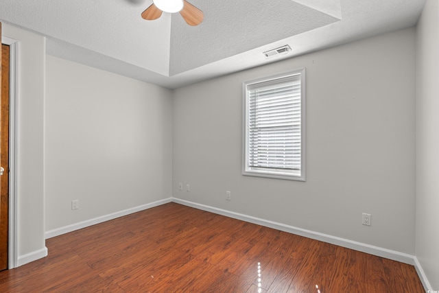unfurnished room featuring ceiling fan, a textured ceiling, visible vents, wood finished floors, and baseboards
