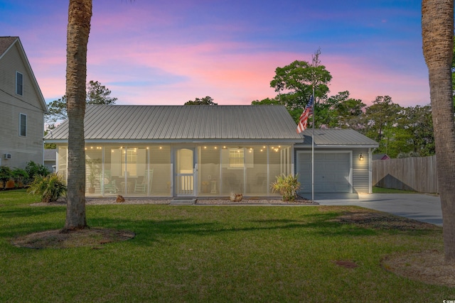 view of front facade featuring metal roof, a lawn, a garage, fence, and concrete driveway