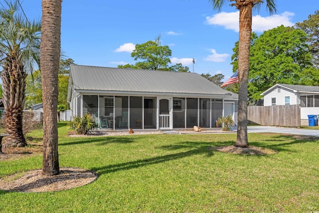 back of house with fence, a yard, a sunroom, and driveway