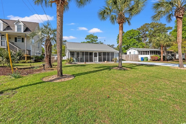 view of yard featuring fence, concrete driveway, and a sunroom