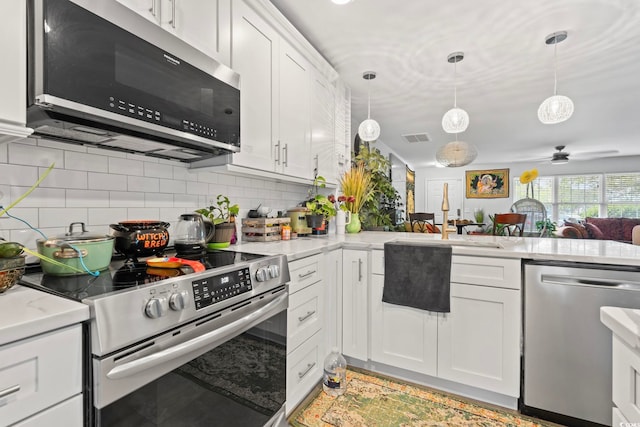 3564 Evergreen Way Unit 3564, Myrtle Beach, SC 29577 - kitchen featuring appliances with stainless steel finishes, decorative backsplash, a ceiling fan, white cabinetry, and pendant lighting