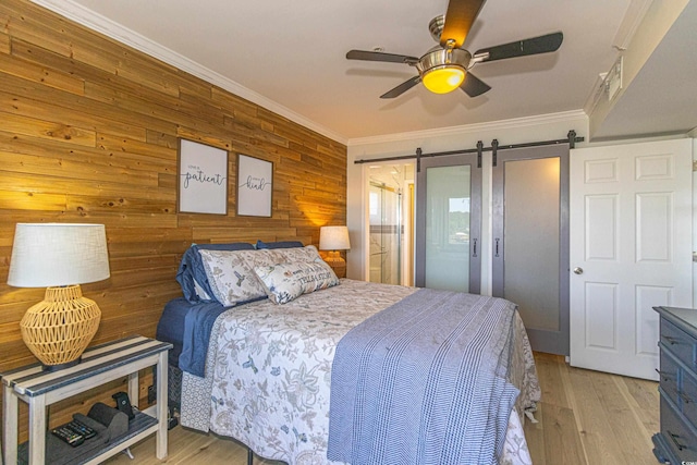 4560 Greenbriar Dr Unit 306B, Little River, SC 29566 - bedroom with a barn door, ornamental molding, wooden walls, light wood-style floors, and a ceiling fan